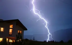 In einem Gewitter ist ein Blitz neben einem Wohnhaus zu sehen