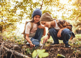 2 Kinder spielen im Wald und untersuchen den Boden