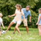 Elternpaar und ihre 2 Kinder spielen im Garten Fußball